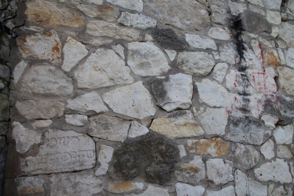 Частини мацев зі старого єврейського цвинтаря в Казімєжі Дольному, використані для побудови муру навколо шкільного стадіону